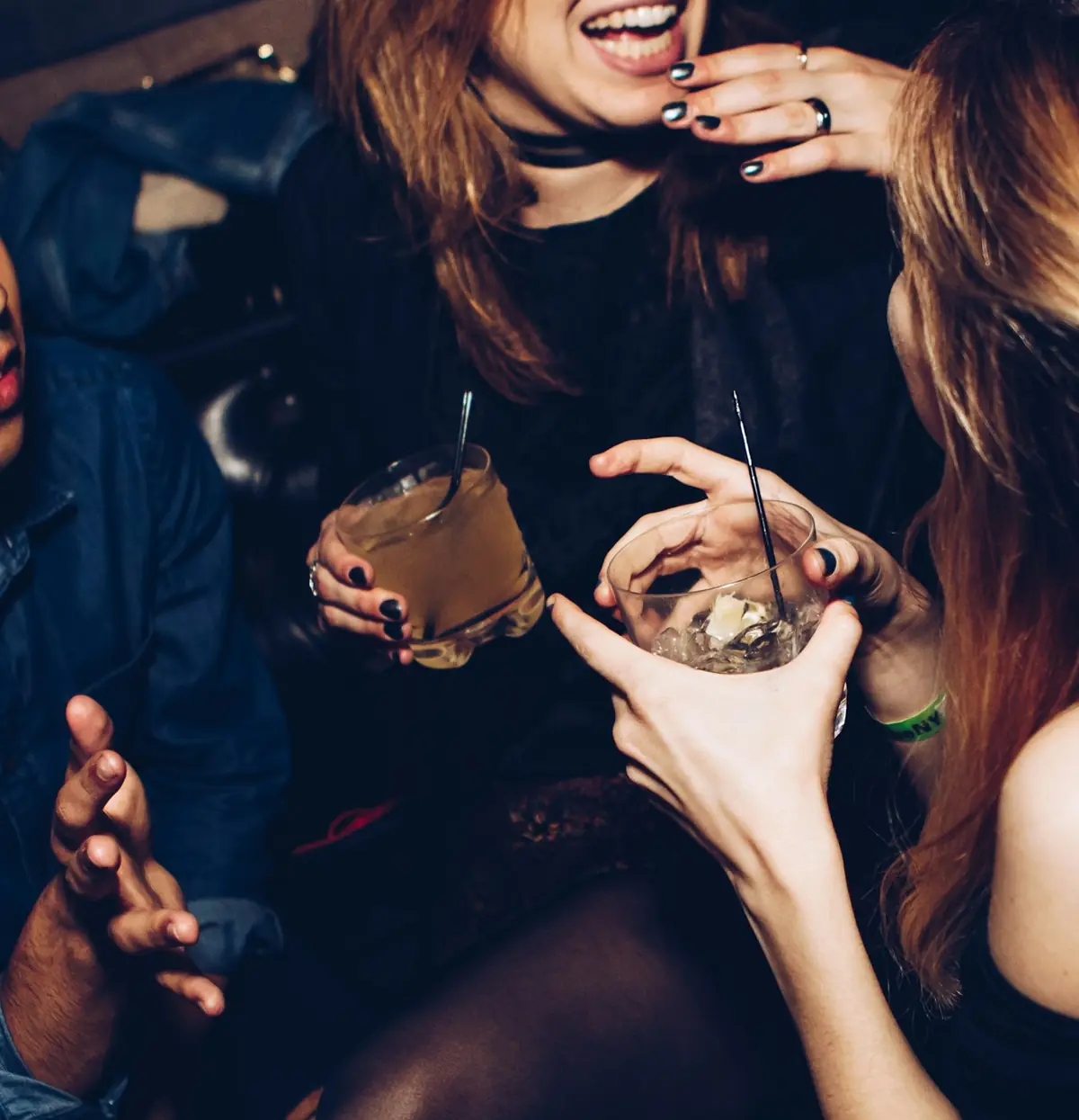 Mulheres jovens adultas brindando com drinks numa festa à noite.